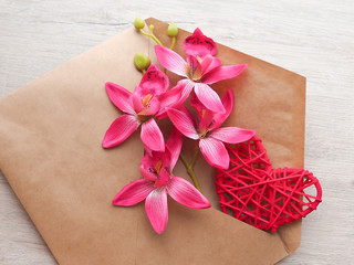 gift pink flowers and heart in envelope Kraft on a light backgro