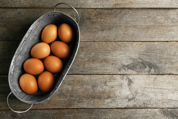 Raw eggs in bucket on wooden background