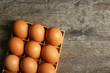 Raw eggs in box on wooden background