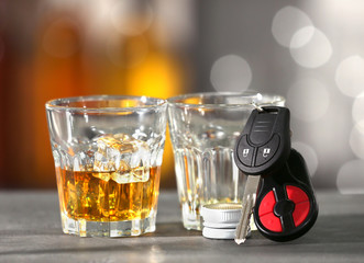 Glasses with alcohol and car keys on grey table
