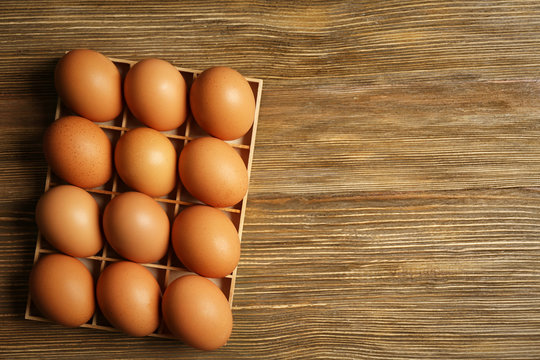 Raw eggs in box on wooden background