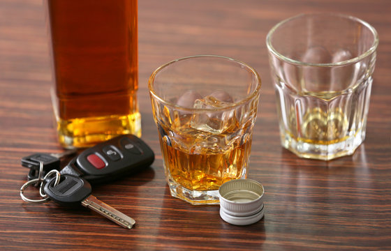 Glasses with alcohol and car keys on wooden background