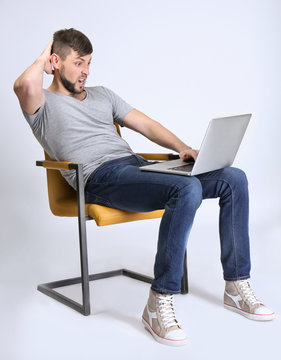 Handsome young programmer with laptop on color background