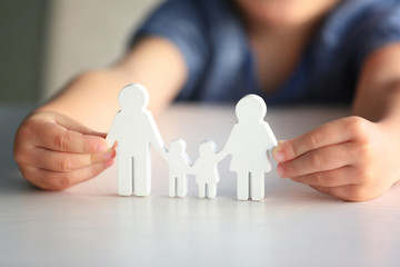 Fototapeta na wymiar Child holding figure in shape of happy family, closeup. Adoption concept