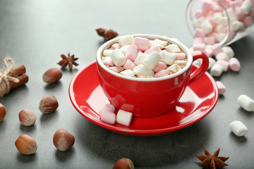 Cup of hot cocoa with marshmallows on color background