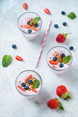 Fruit smoothy with blueberries, strawberry and muesli decorated with fresh mint leaf on bright concrete background. Top view