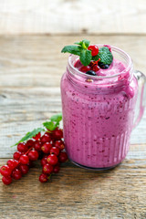 Glass jar with berry smoothies and green mint.