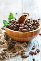 Ground coffee and roasted coffee beans in a wooden bowl.