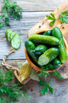 Delicious salted cucumbers, dill and spices in a wooden bowl.