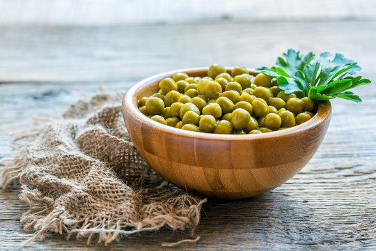 Canned green peas in a wooden bowl.