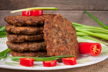 liver pancakes or cutlets with chili pepper and green onions on a wooden background