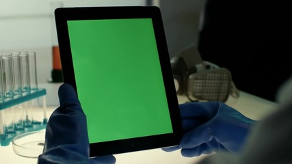 Scientist using tablet PC with green screen in modern laboratory on a background of test tubes and protective mask - Powered by Adobe