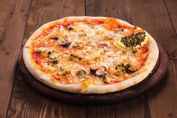 delicious Seafood Pizza on a wooden table (close)