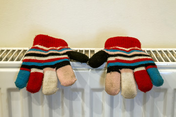 Childs knitted gloves drying on heating radiator after winter da