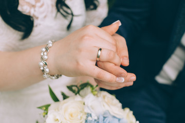 hands of bride and groom with bouquet