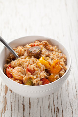 Jambalaya in a white ceramic bowl on a weathered wood white background vertical shotJambalaya in a white ceramic bowl on a weathered wood white background top view