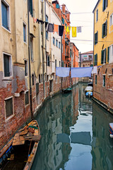 Fototapeta na wymiar Typical Venice canal with moored boats, colorful buildings and stretched out clothes to dry