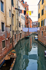 Typical Venice canal with moored boats, colorful buildings and stretched out clothes to dry