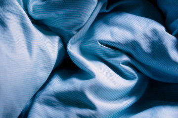 Wrinkled blue bed sheets on a morning as a background
