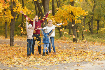 Naklejka na ściany i meble Happy family playing with leaves in beautiful autumn park