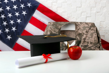 Graduation hat, apple and diploma on white table. USA military education concept