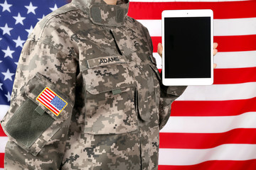 Close up view of female soldier holding tablet computer, with USA flag on background