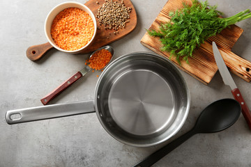 Stainless saucepan, parsley and lentil on grey kitchen table