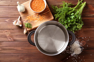 Stainless saucepan, parsley and lentil on wooden background