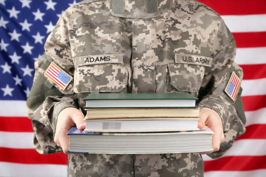 Close up view of female soldier holding books, with USA flag on background