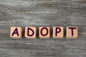 Cubes with word ADOPT on wooden background