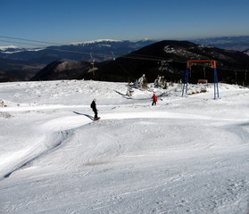 Snowboarder descends and rises to the skier lifts on snowy road