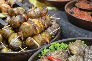 Street food.Unpeeled and sliced potatoes roasted with bacon on sticks are on food stall. Christmas fair in Ukraine Christmas fair in Ukraine.