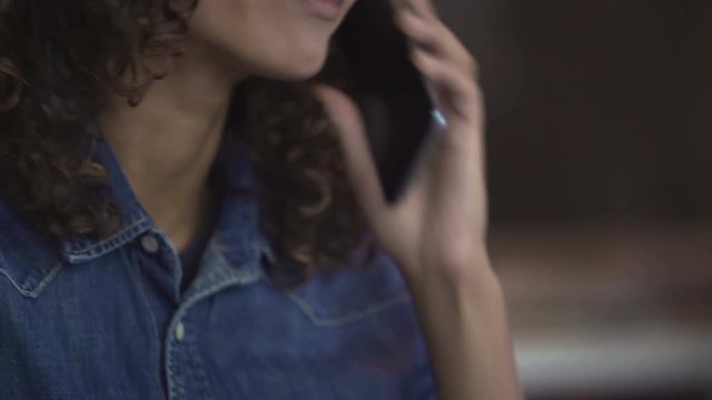 Beautiful curly biracial woman talking on smartphone and smiling, emotions