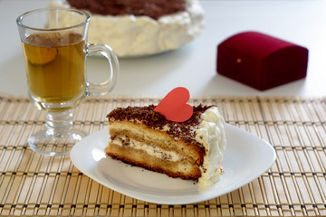 Piece of Valentine's Day cake with cup of tea on wooden napkin