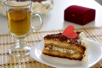 Piece of Valentine's Day cake with cup of tea on wooden napkin
