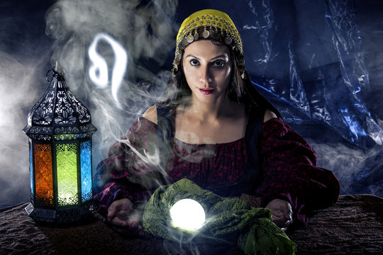 Psychic or fortune teller with crystal ball and horoscope zodiac sign of Leo