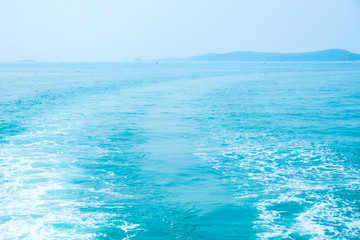 Foam waves behind ferry in the turquoise sea water. Horizon