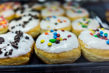 Display of white glazed donuts on tray topped with candy coated