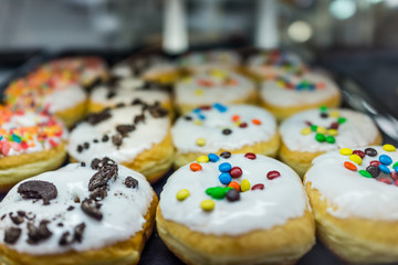 Display of white glazed donuts on tray topped with candy coated