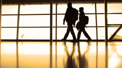 People following to boarding in the airport terminal in front of window, silhouette, warm