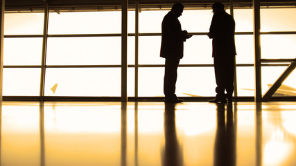 Fototapeta na wymiar Passengers waiting to boarding in front of window in airport, silhouette, warm