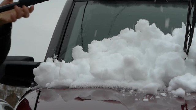 Person scrapes car windshield from snow after snow blizzard
