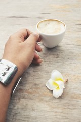 Selfie of coffee on hand with white frangipani flower