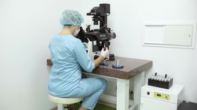 Embryologist performing icsi procedure on robotic micromanipulator in laboratory.