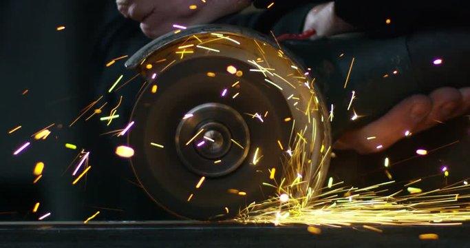 locksmith with a laser cuts in half a sheet of steel causing sparks.The laser heat Nicks iron up to get clean cuts and perfect for buildings with wrought iron.Concept: industry,technology,engineering.