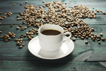 Cup of black coffee with beans scattered around