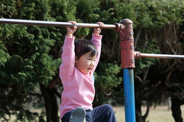 Fototapeta premium 鉄棒にぶら下がる二歳児