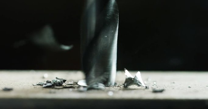 Macro shot of a drill that pierces a sheet of iron or steel. The tip of the metal drill with a circular motion pierces the material. Concept:engineering,industry,technology, locksmith and construction