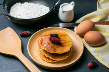 Pancakes with fresh mulberry and honey on black stone background