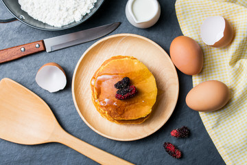 Pancakes with fresh mulberry and honey on black stone background